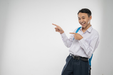 a boy in junior high school uniform smiling with finger pointing when carrying a backpack with copyspace on an isolated background