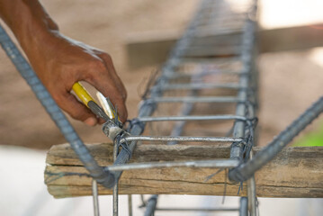 method of tying reinforcing steel bars, tightening wire on rebar using a pincers for formwork construction, selective focus at wire and head of a pincers.