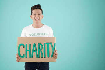 Studio portrait of smiling young charitable foundation volunteer holding big placard
