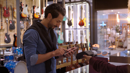 An upwardly mobile Muslim man using smart payment to pay for a product at a sale terminal with nfc identification payment for verification and authentication