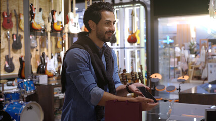 An upwardly mobile Muslim man using smart payment to pay for a product at a sale terminal with nfc identification payment for verification and authentication