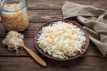 Pickled sauerkraut with carrots on a wooden table.