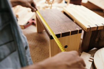 Close-up image of carpenter measuring drawer front with tape measure