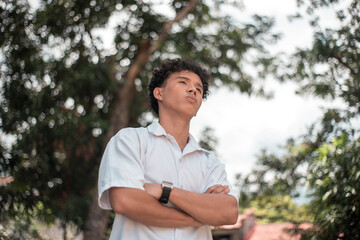 A young man of mixed asian race in deep thought or contemplation while outdoors.