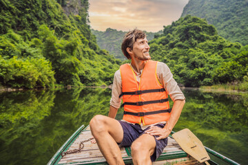 Fototapeta premium Man tourist in Trang An Scenic Landscape Complex in Ninh Binh Province, Vietnam A UNESCO World Heritage Site. Resumption of tourism in Vietnam after quarantine Coronovirus COVID 19