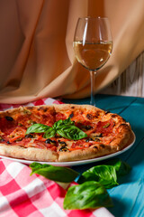 Fresh italian pizza with salami and black olives and other food on the background. Blue colored wooden table.