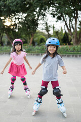 two asian girl going on her in-line skates in the park