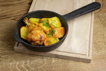 Roasted chicken with potatoes and spices in a frying pan. Whole dinner in a frying pan