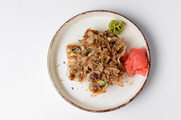 Tuna sushi in white dish served with wasabi sauce, pickled ginger. Over white background.
