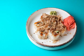 Tuna sushi in white dish served with wasabi sauce, pickled ginger. Sushi set with tuna shavings. Over blue background.