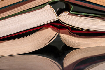 Binding of stacked books on a reflective surface, close-up