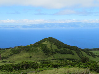 view to a hill from pico island, faial island in background