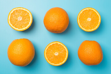 Top view photo of six staggered oranges three whole and three halves on isolated pastel blue background
