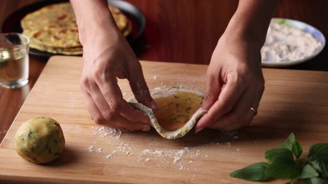 Preparation of Aloo Paratha or roti parantha chapati  4K slow motion video footage Punjab, North India. Female hand rolling whole wheat dough mashed potato stuffing rolling pin vegetarian Indian food 