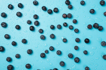 Overhead photo of heap of blueberries everywhere and drops of water isolated on the blue background