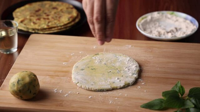 Preparation of Aloo Paratha or roti parantha chapati  4K slow motion video footage Punjab, North India. Female hand rolling whole wheat dough mashed potato stuffing rolling pin vegetarian Indian food 