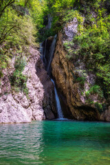 A scenic stream of a waterfall falling among a rocky gorge. Agur river waterfalls in Khosta microdistrict, Russia. Travelling, hiking, mountain activities, outdoors and scenic destinations.