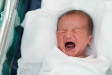 close up of crying neew born infant asleep in the blanket in delivery room
