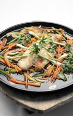 chinese style steamed fish fillet with vegetables on hot plate