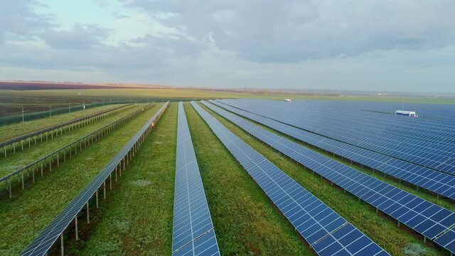 Solar panels at a suburban solar power plant. Farm fields on the background. Silicon photovoltaic cells in polycrystalline solar modules. High quality. 4k footage.