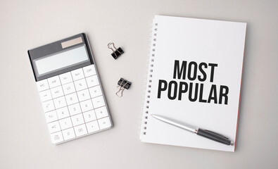The word most popular is written on a white background next to a pen ,calculator and reports. Business concept
