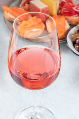 A glass of rose wine with salmon sandwiches and cheeses. Spanish tapas in a bar. A close-up of a summer drink at a party