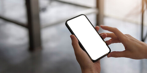 Mockup image blank white screen cell phone.women hand holding texting using mobile on desk at home...