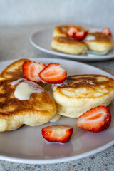 fluffy pancakes on a plate are stuffed with strawberries and poured with jam. thick pancakes for breakfast