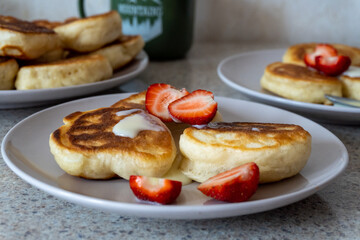 fluffy pancakes on a plate are stuffed with strawberries and poured with jam. thick pancakes for breakfast