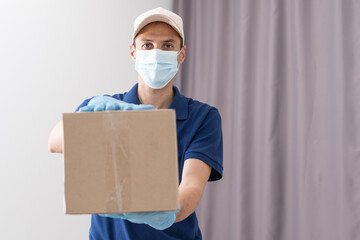 Fototapeta na wymiar Delivery guy with protective mask and gloves holding box with groceries