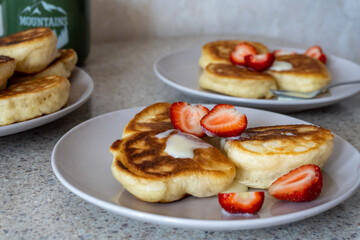fluffy pancakes on a plate are stuffed with strawberries and poured with jam. thick pancakes for breakfast