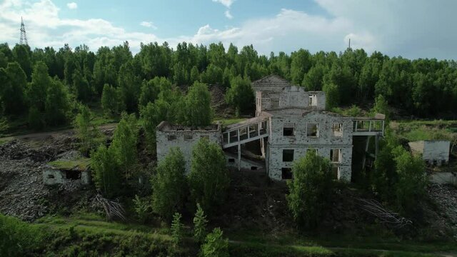 an old abandoned building in a coniferous forest on a mountain, a former industrial mine in Khakassia, Russia. Tuimsky failure. location for depressing horror movies. drone flyby, aerial footage