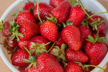 Red ripe strawberries in the bowl, top view