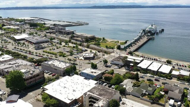 Cinematic 4K drone dolly out shot of the downtown Edmonds commercial area, Kingston ferry loading cars at the terminal, waterfront marina, near Seattle Washington, in Snohomish County
