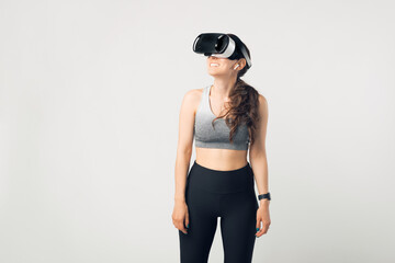 Photo of young sport woman wearing sportswear and VIRTUAL REALITY HELMET over white background