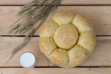 Wheat ears on a wooden table. A loaf of homemade bread and a glass of milk on a wooden background. Harvesting concept