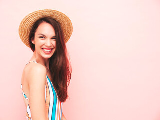 Young beautiful sexy smiling  hipster woman in posing near pink wall in studio. Trendy model in colorful summer swimwear bathing suit. Positive model going crazy.Happy and cheerful in hat