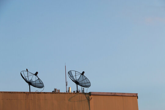 Dual satellite receivers on the building and blue sky background