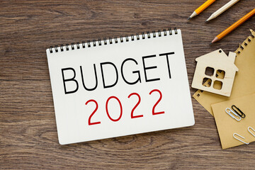 Budget 2022. text on a wooden table, on white paper near the figure of a house made of wood