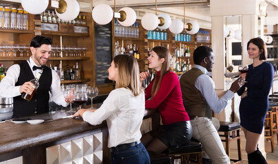 Glad girl and man are relaxing near bar counter and drinking alcohol in restaurant