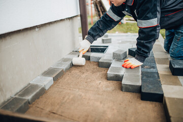 Laying tiles outside the house on the ground - arranging and installing footpaths in the backyard -...
