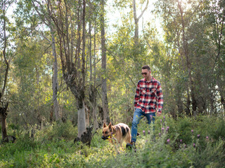 Young man walking with his dog in the woods. Selective focus