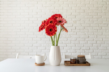 Bright gerbera daisies in white vase on kitchen table, minimal style