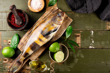  Raw fish sea bass or lingcod and seasonings for cooking it on an old plank background top view, free space for text