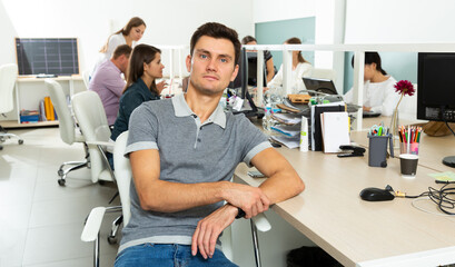 Portrait of male manager sitting at his workplace in office
