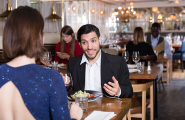 Smiling bearded man with female colleague on friendly meeting over dinner in restaurant
