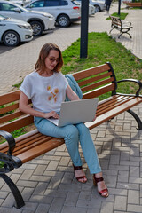 a girl sitting on a bench with a gray laptop