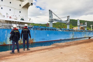 Fototapeta na wymiar Two dockers mooring a cargo ship in the port of Bilbao