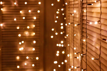 garland with yellow bulbs hangs on wooden screen. New Year and Christmas background