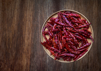 Red hot dry chili peppers in wood bowl on wooden floor background, rustic style